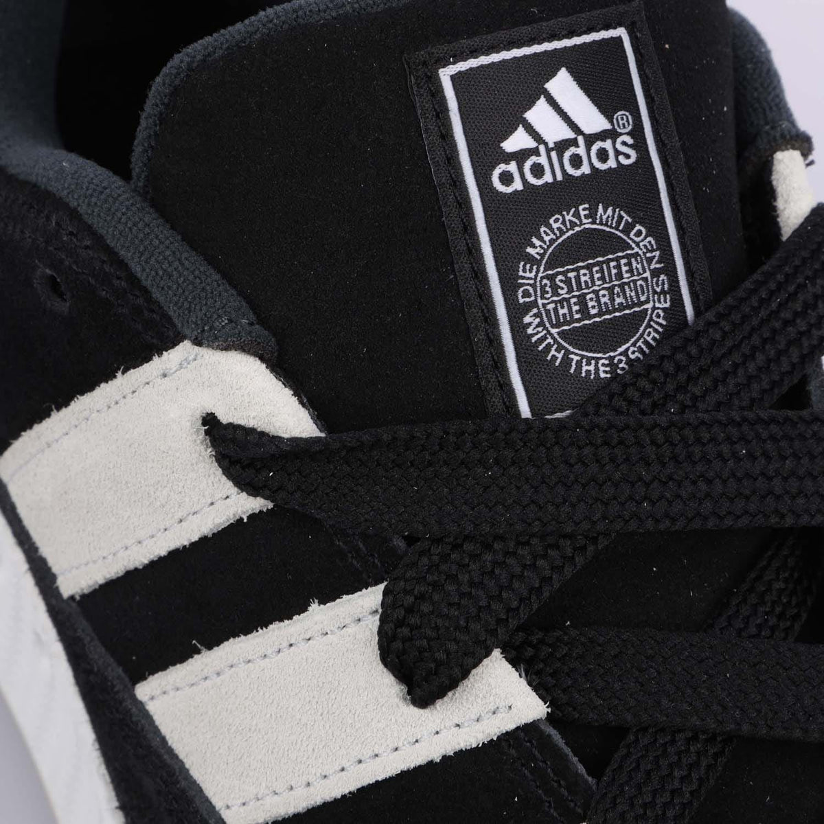 Close-up of adidas tongue label on black and white lace-up trainers