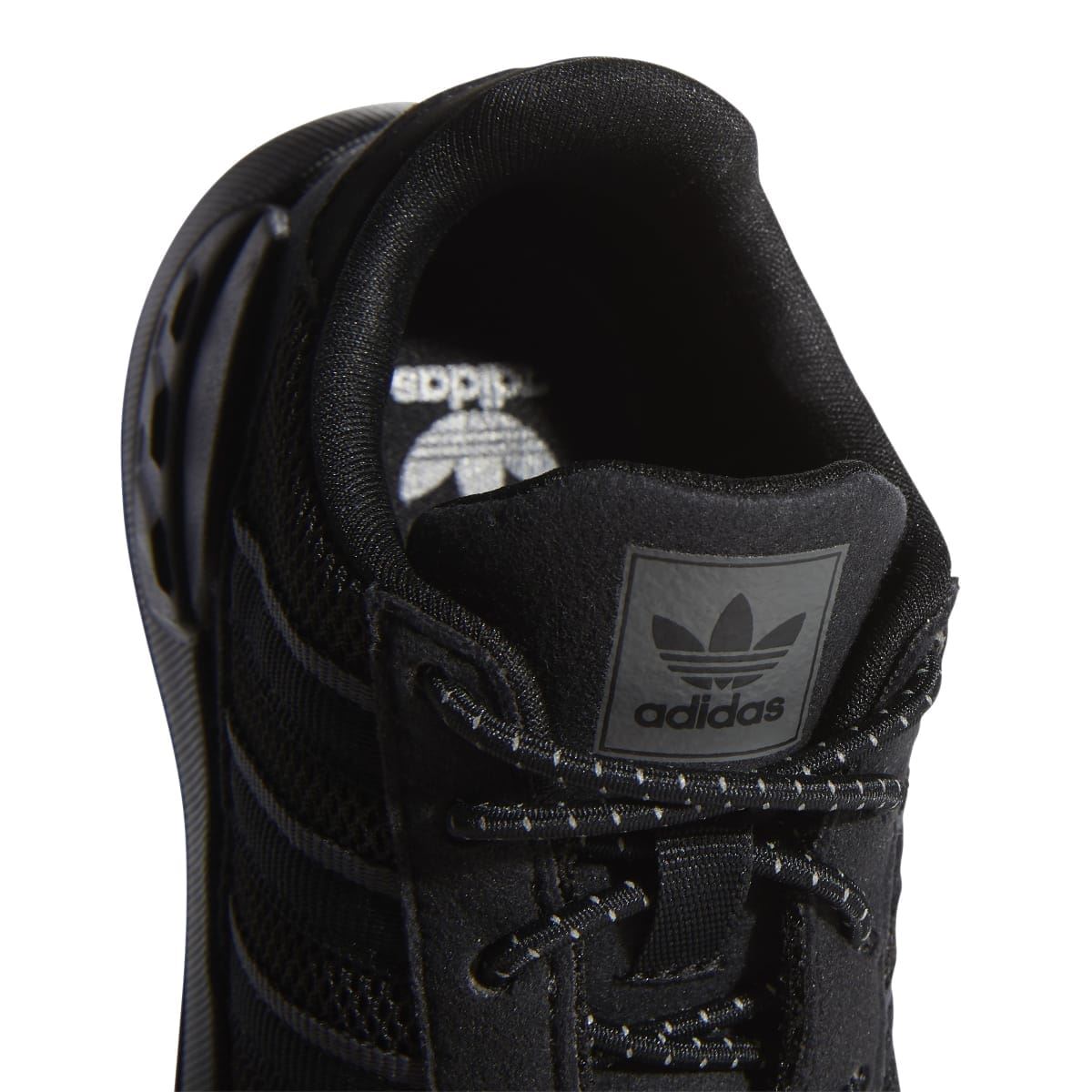 Infant trainer heel lining showing adidas logo and padded collar in black.