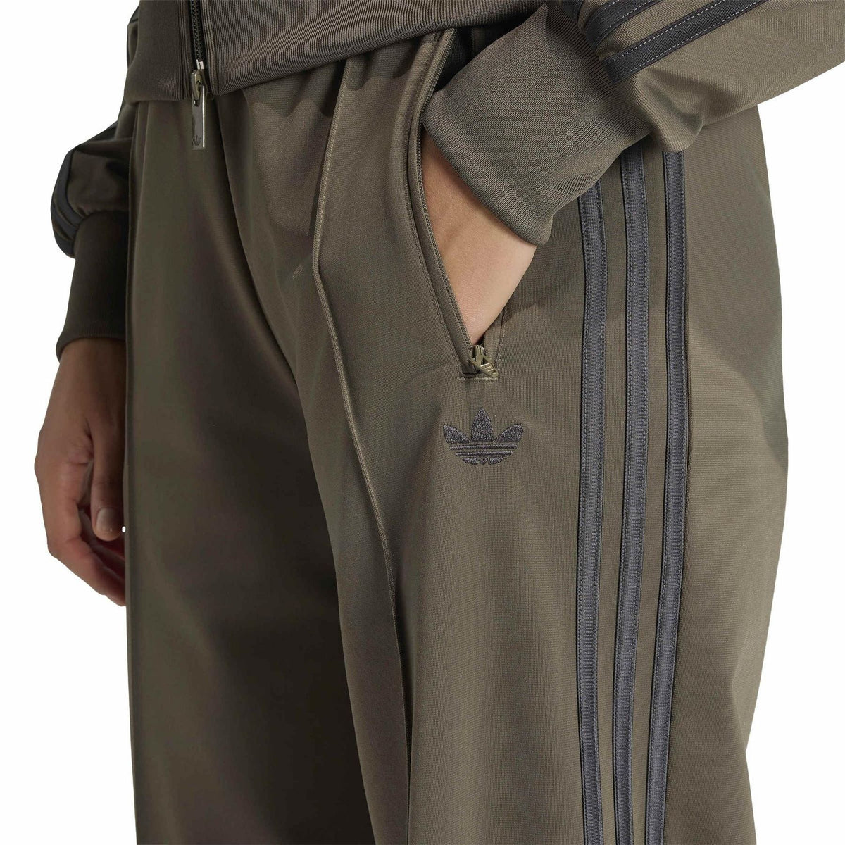 Olive green woven joggers with Adidas trefoil logo and zip pocket