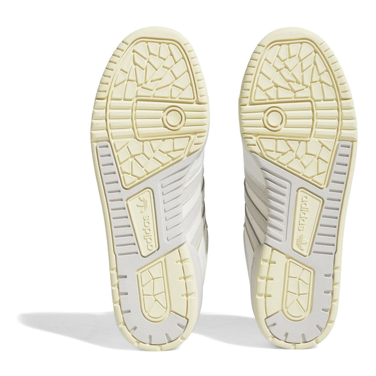 Cream outsole bottoms of adidas low-top trainers with textured tread and branding.
