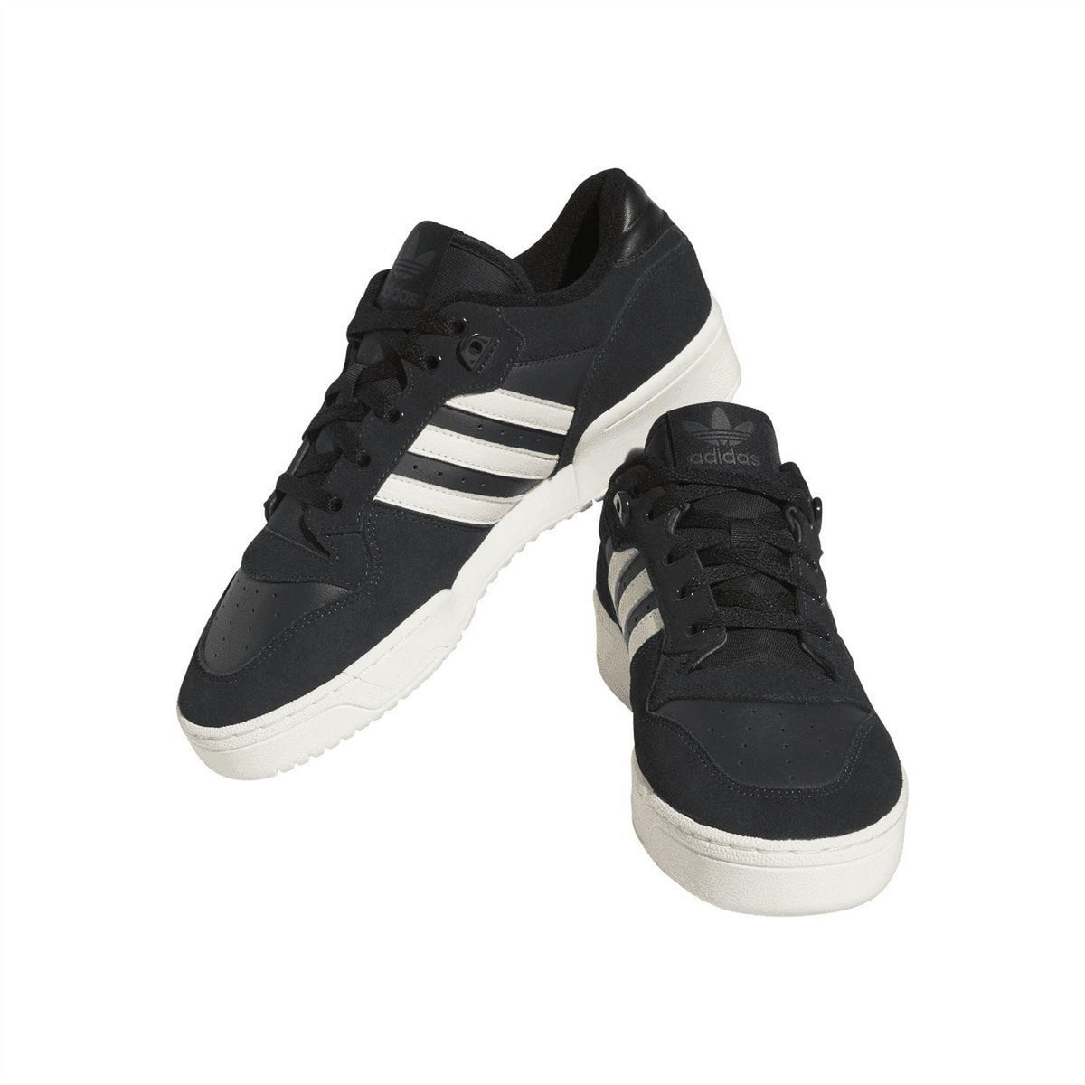 Black low-top trainers with white stripes and chunky white midsole, angled view