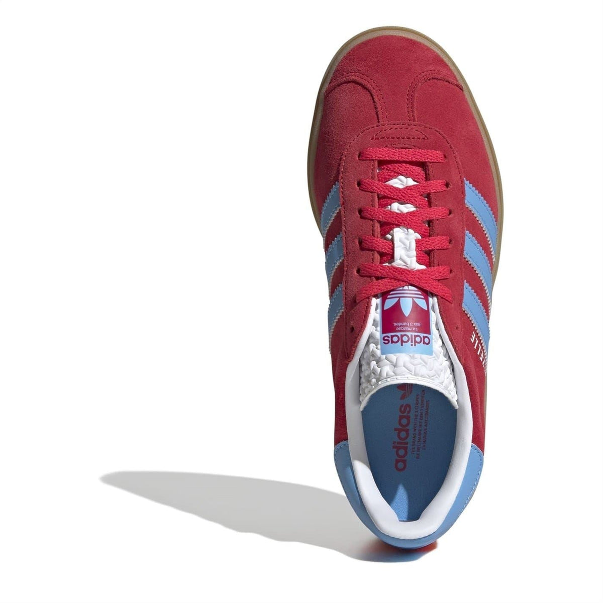 Red Gazelle low-top sneakers with blue stripes, white tongue label, and lace-up front