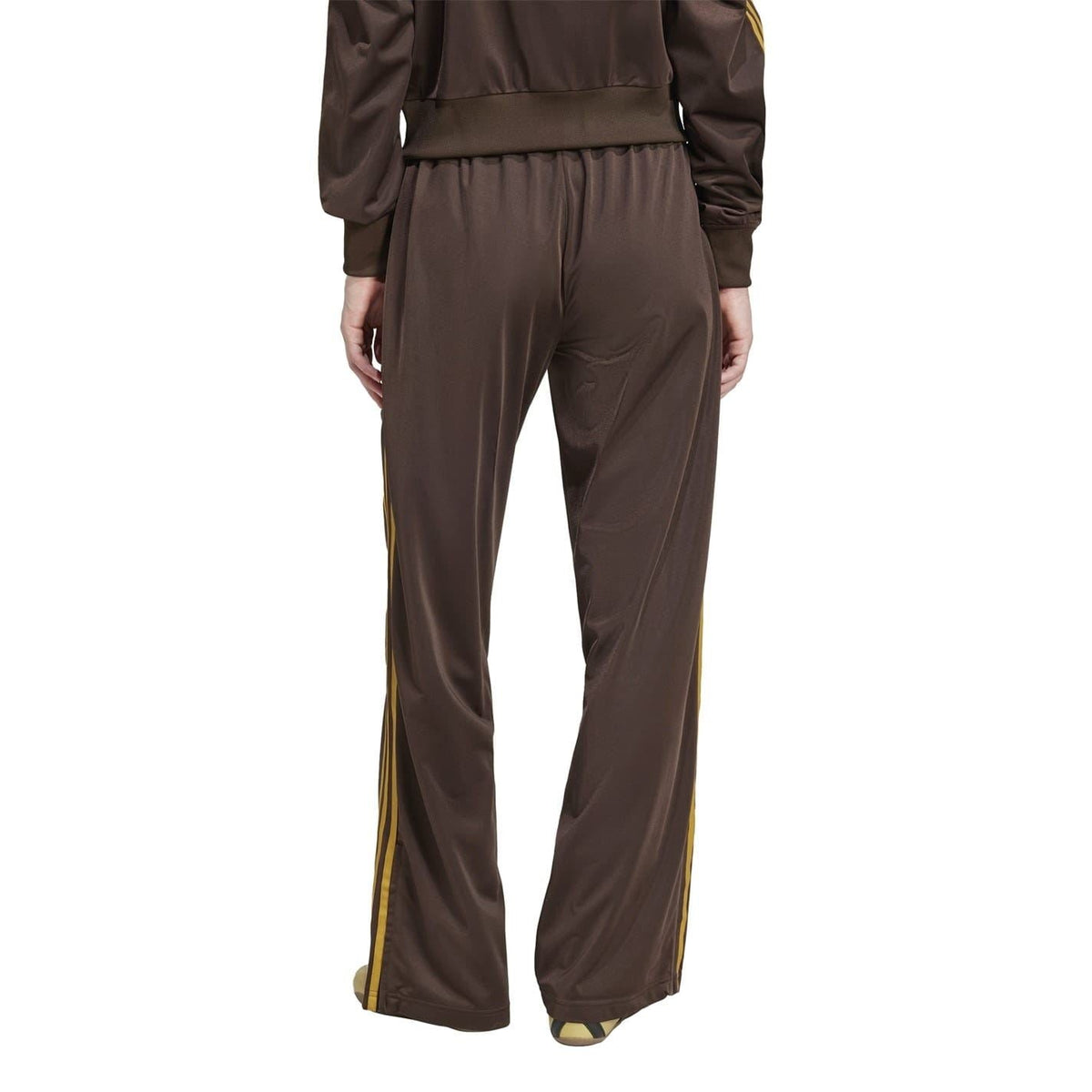 Brown loose track pants with elastic waist, side stripe taping, and trefoil logo