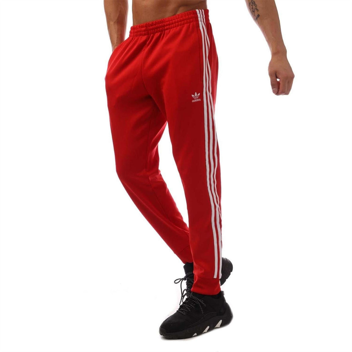 Red adidas Originals SST track pants with white side stripes and elastic cuffs