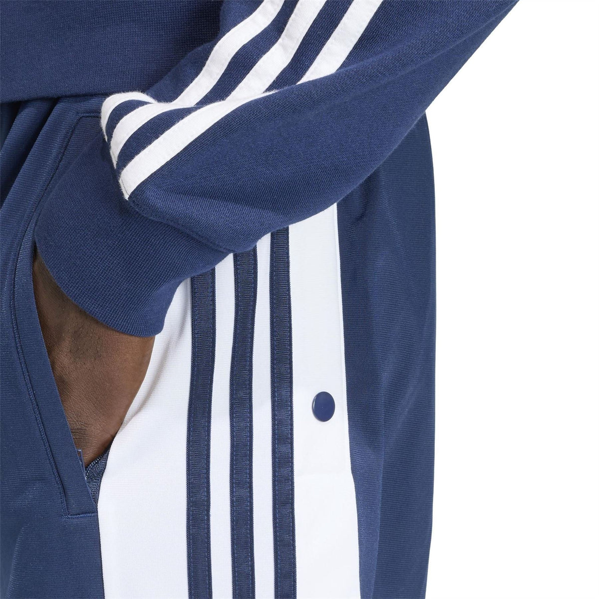 Close-up of indigo track joggers with vertical stripe taping and ribbed open cuff