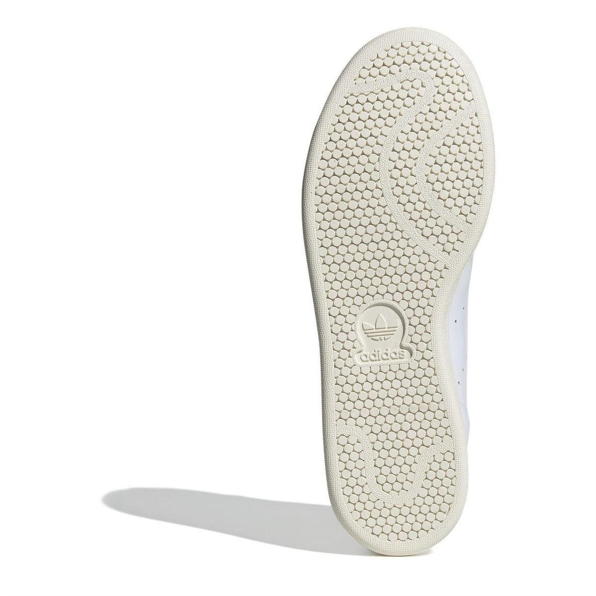 White sneaker outsole with textured tread and adidas branding on the heel
