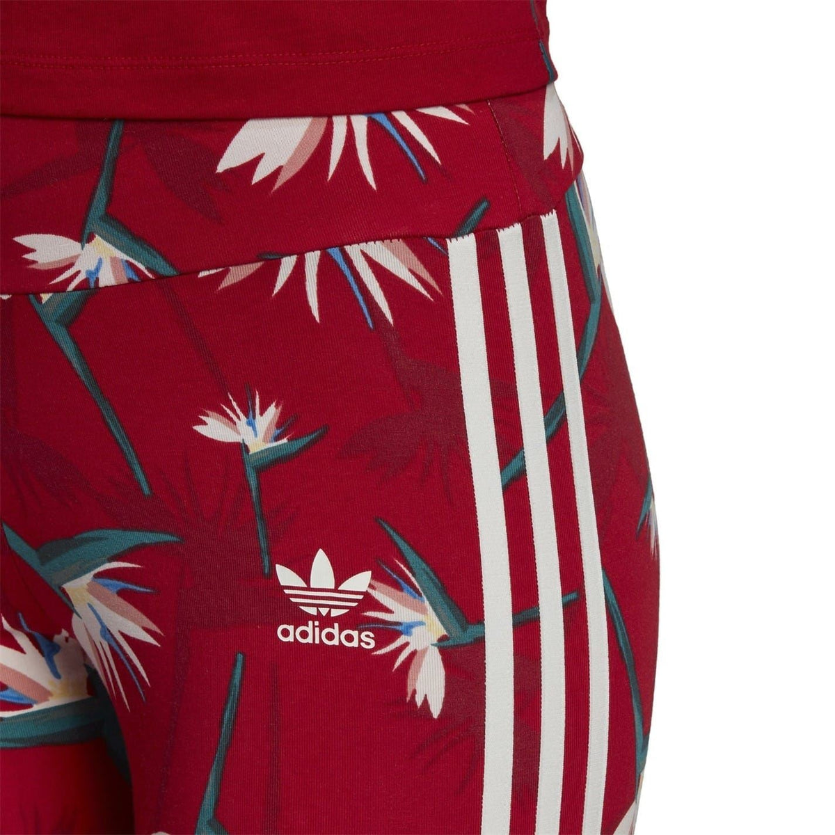 Close-up of red adidas leggings showing tropical print waistband and white side stripes