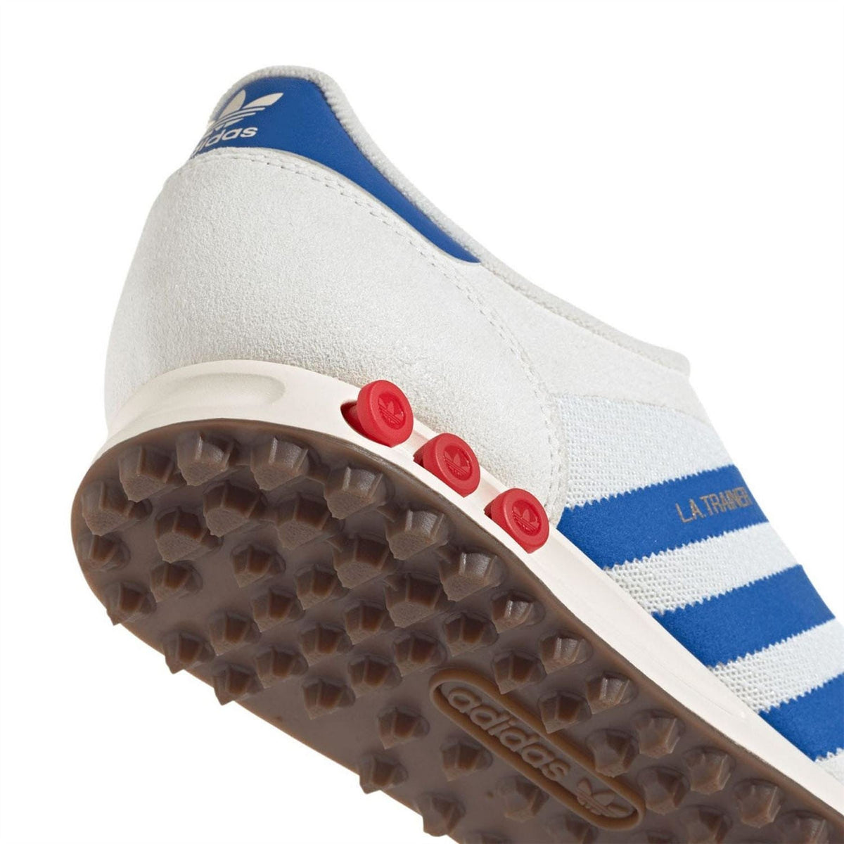Close-up of white adidas Originals trainer outsole with red studs and blue stripe