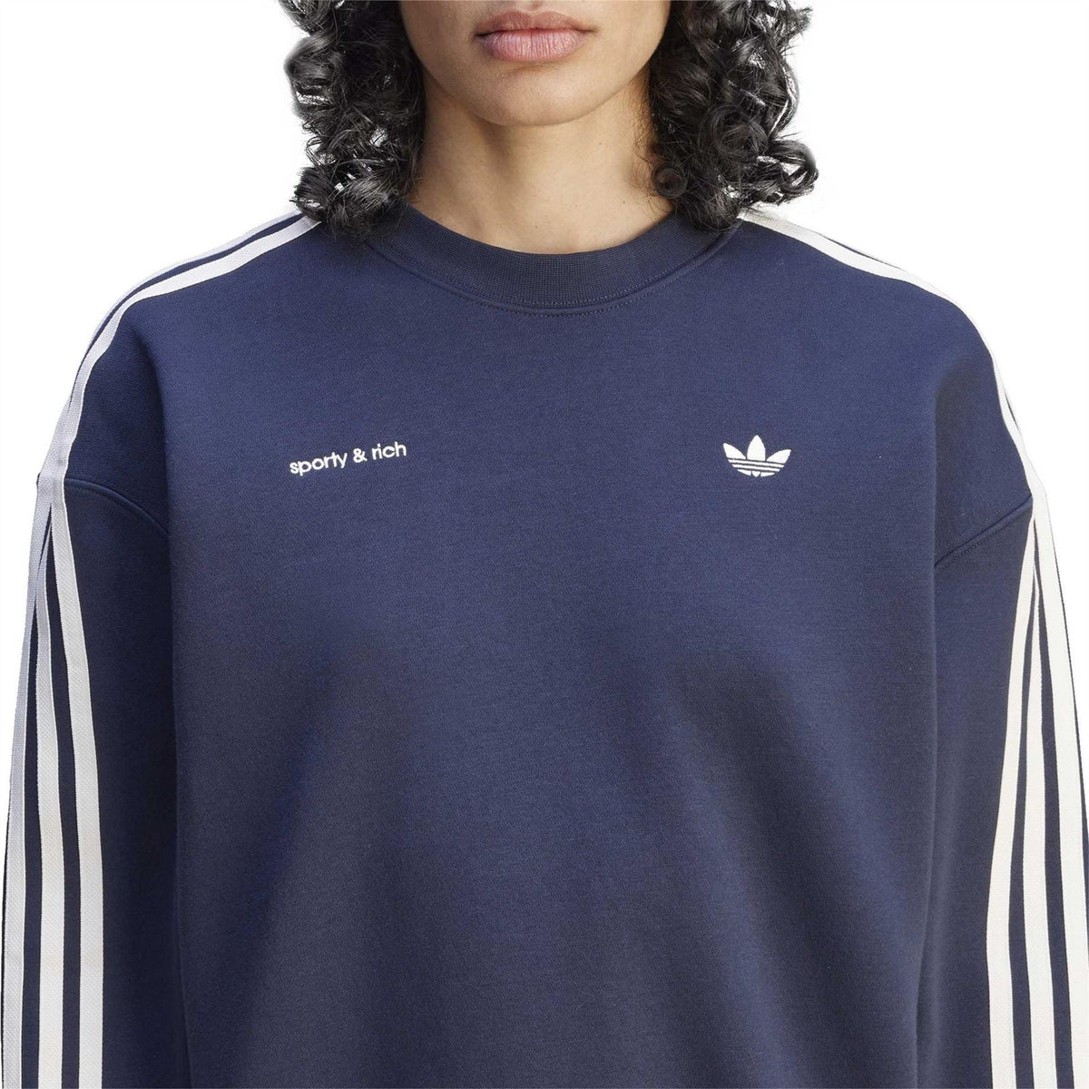 Navy sweatshirt close-up with 'sporty & rich' text and white adidas trefoil