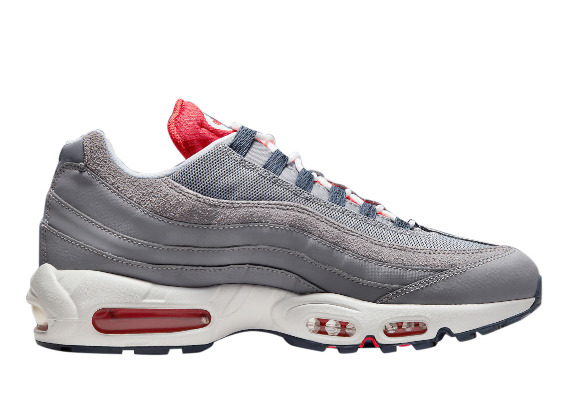 Men's Nike Air Max 95 cement grey lace-up sneaker with red air units and blue heel panel.