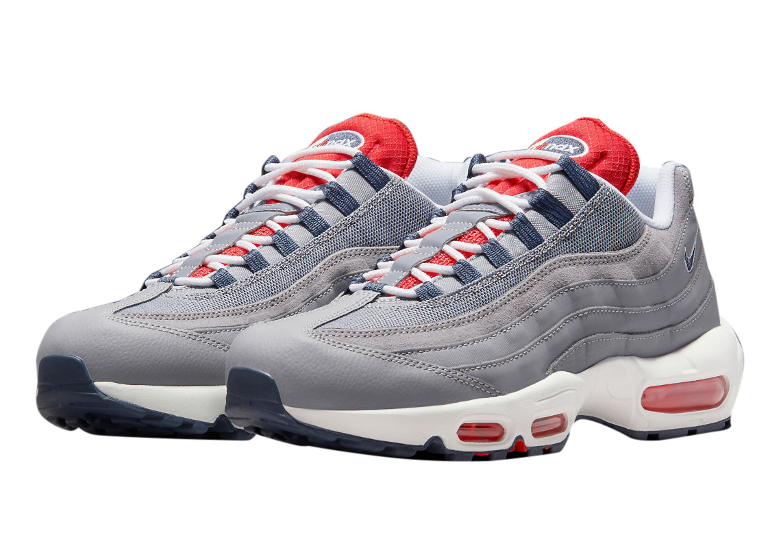 Men's Nike Air Max 95 cement grey sneaker with red lining, blue details, and cushioned sole.