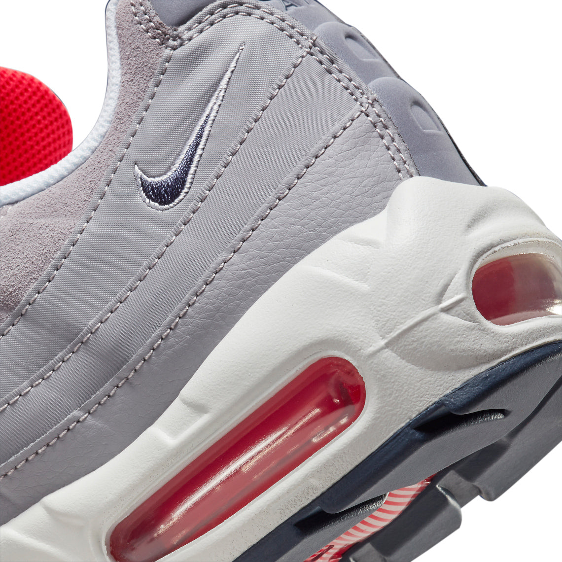 Men's Nike Air Max 95 close-up: grey leather panels, Nike swoosh, and red air window.