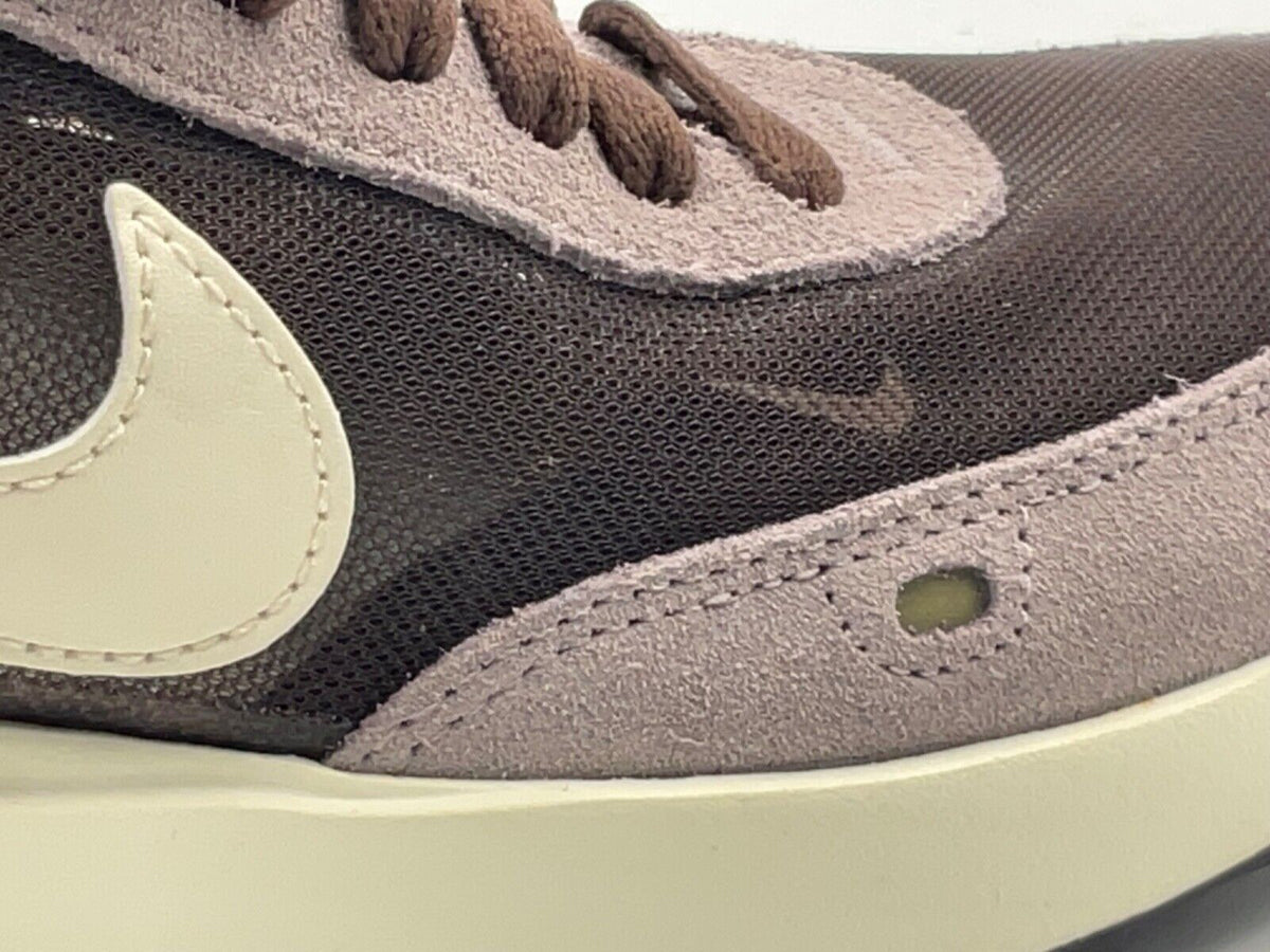 Nike Waffle One upper close-up, textured dark mesh with light beige overlay and eyelets
