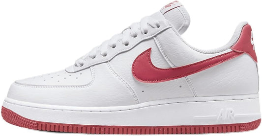 Nike Air Force 1 low-top sneakers in white with pink swoosh and red outsole edge.