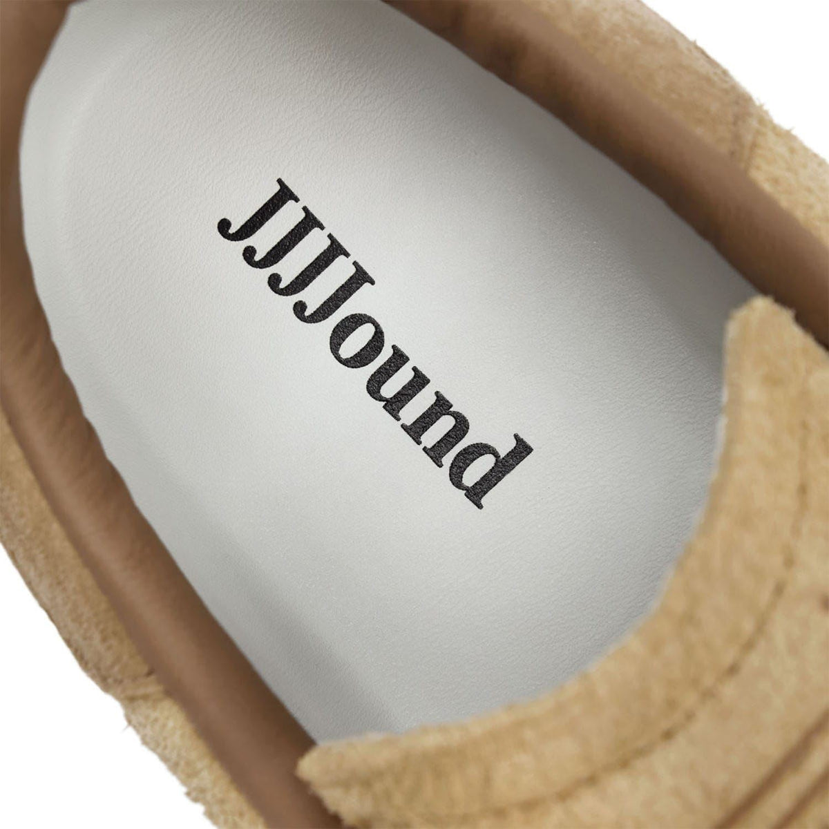White insole with black JJJound lettering inside a brown suede trainer