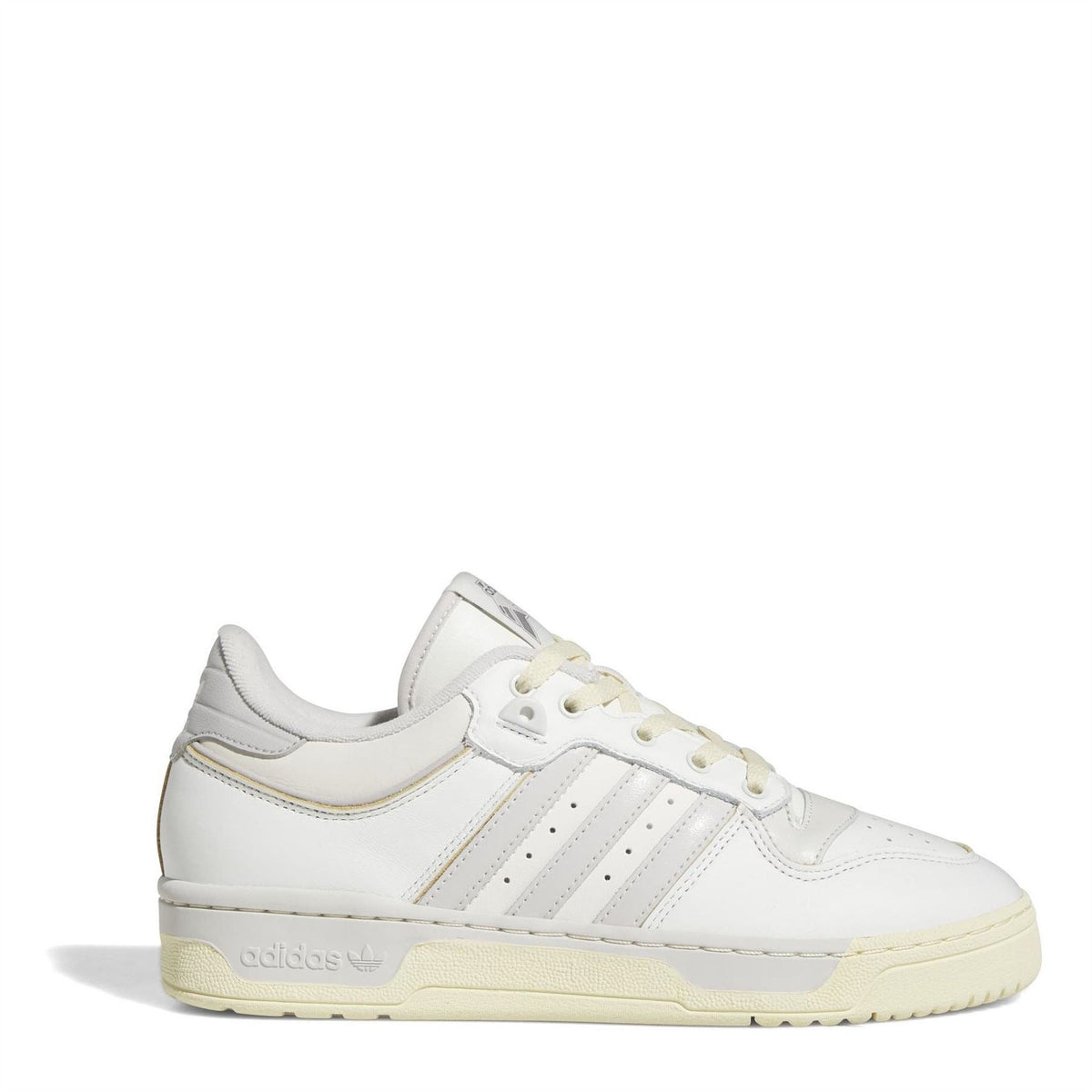 White adidas low-top trainers with three stripes, lace-up front, and gum outsole.