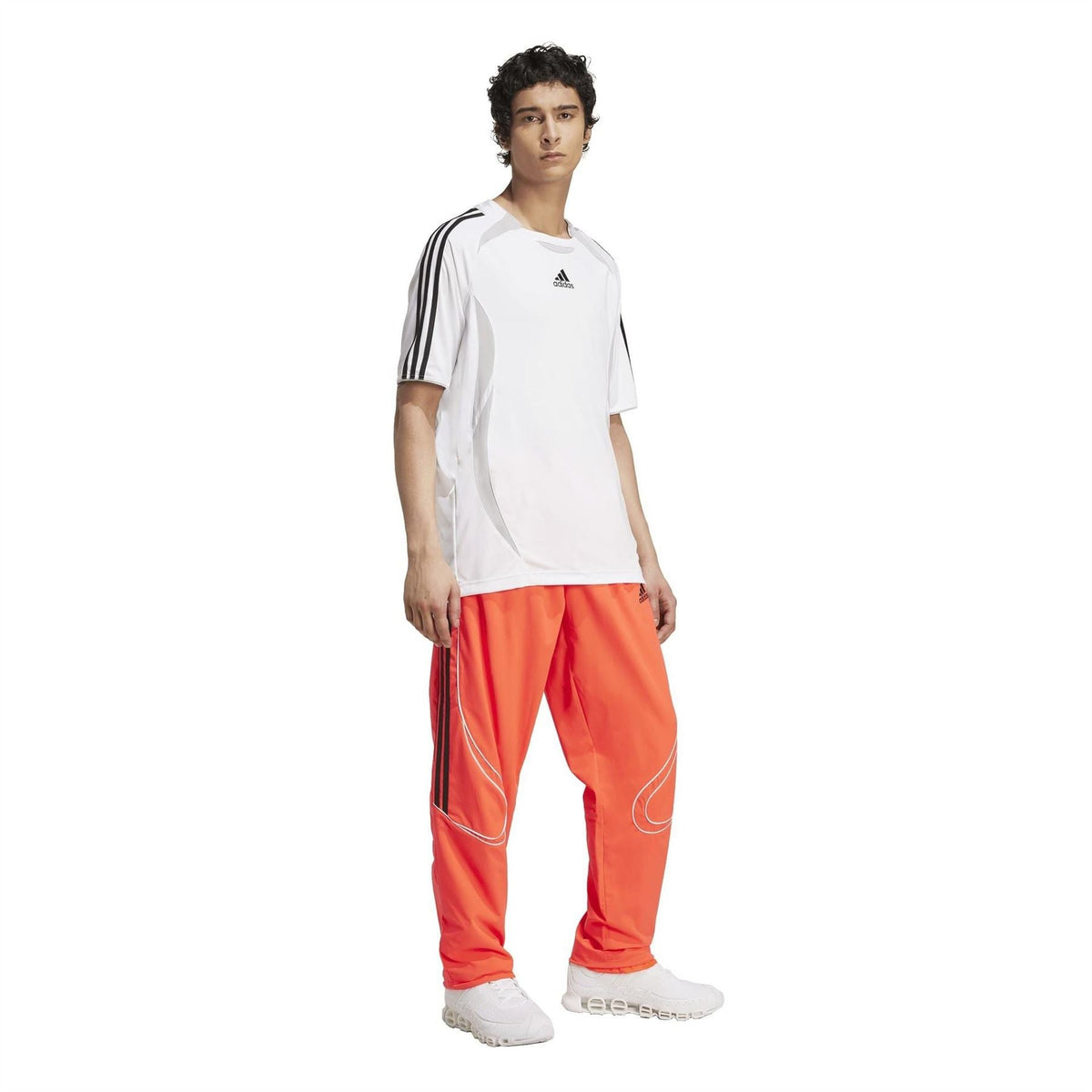 White adidas T-shirt with black sleeve stripes, styled with red track pants