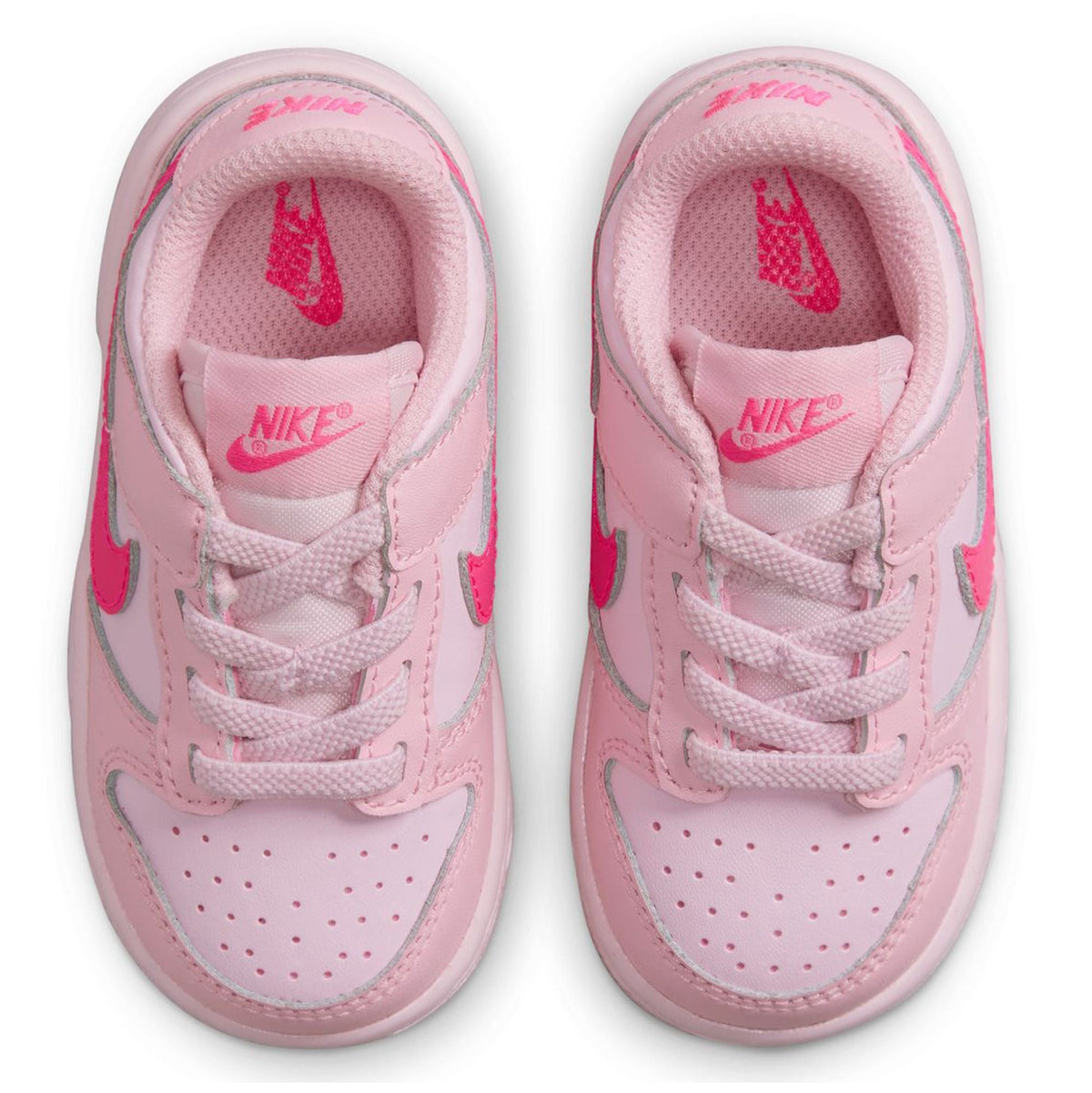 Kids' Nike Dunk Low sneakers, close-up of pink insides with NIKE logos.