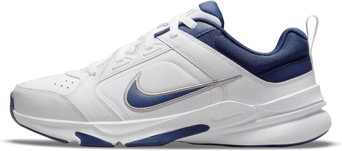 Men's Nike Defy All Day sneakers, side view, white leather with navy swoosh and laces