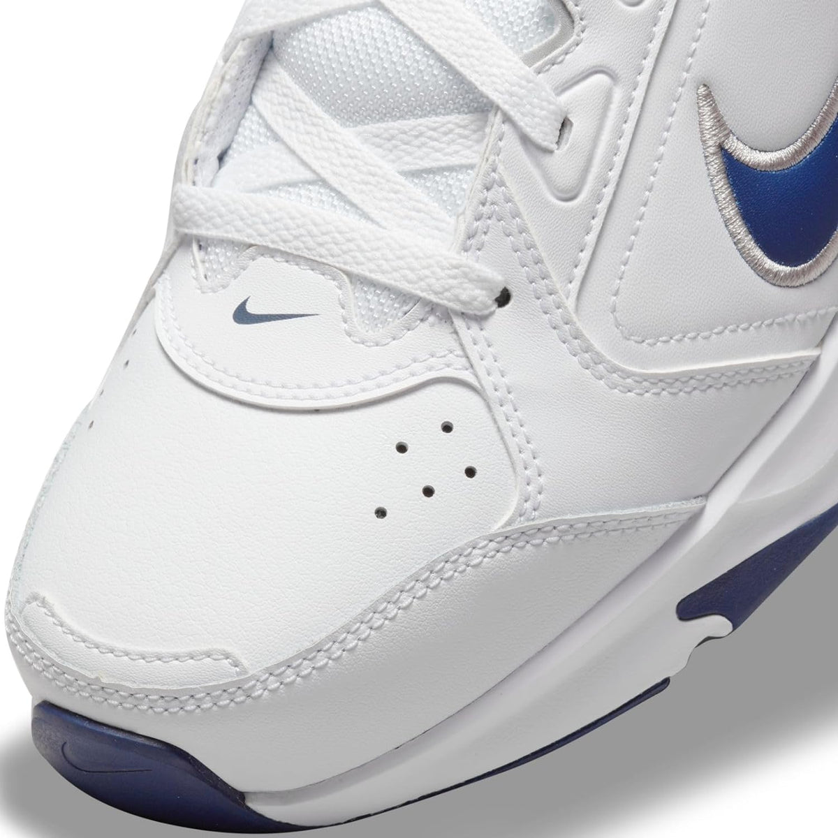 White Nike sneakers with navy swoosh, lace-up front, and textured side panels