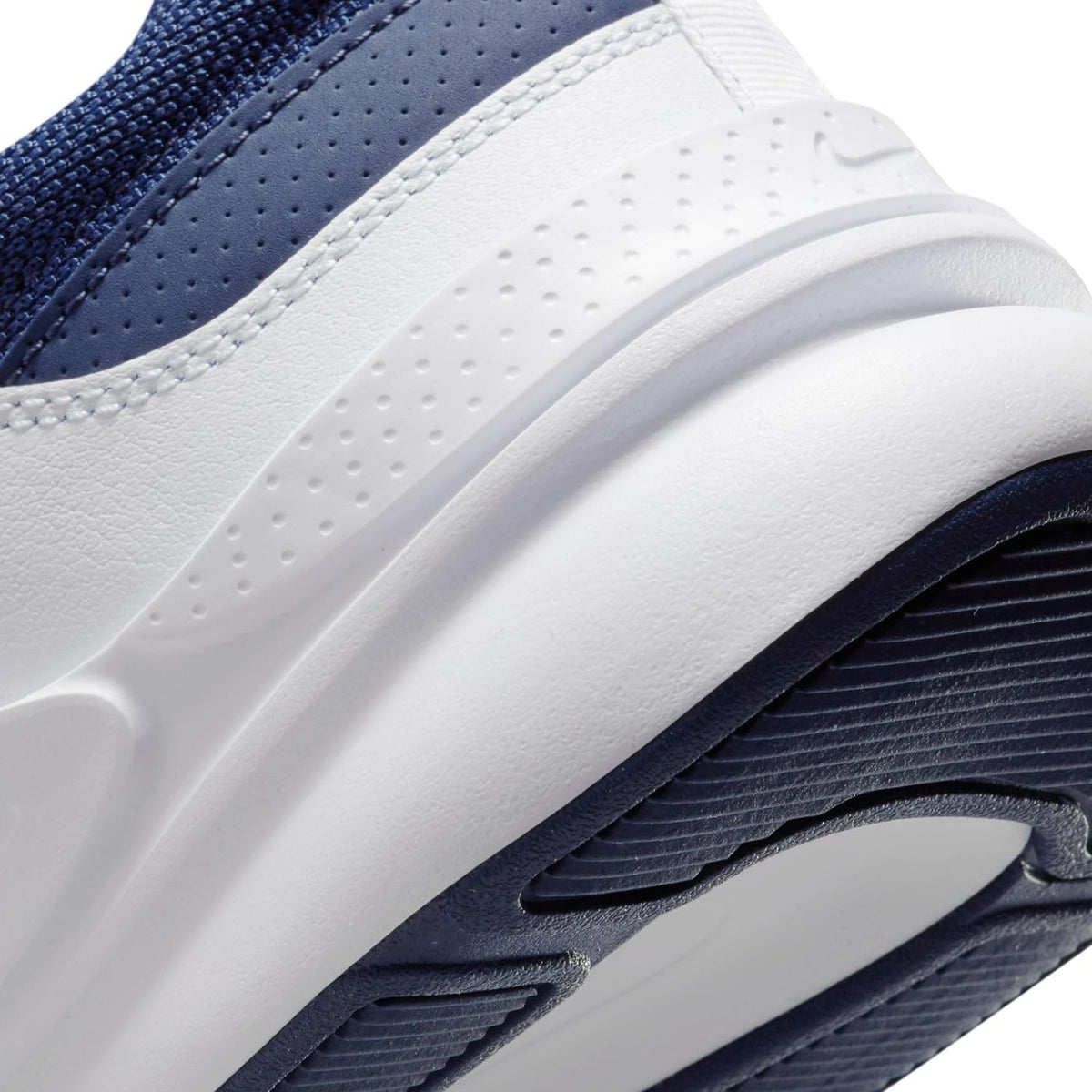 White and navy Nike sneakers with perforated toe panel and thick rubber sole