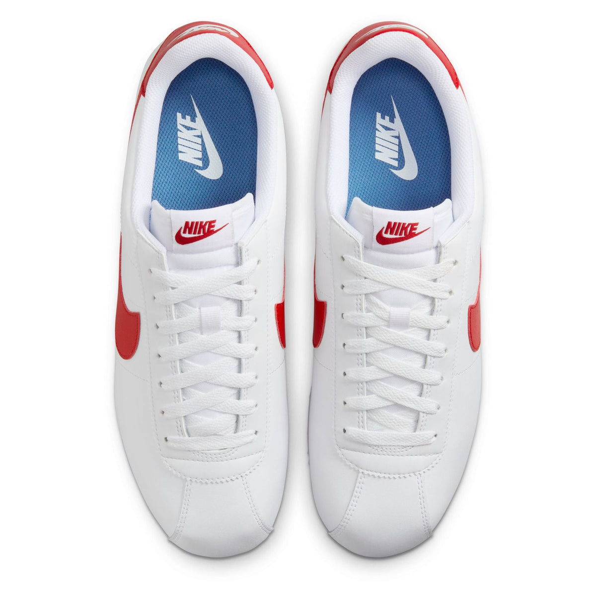 White Nike Cortez sneakers with blue interior, red outsole accents, and lace-up uppers