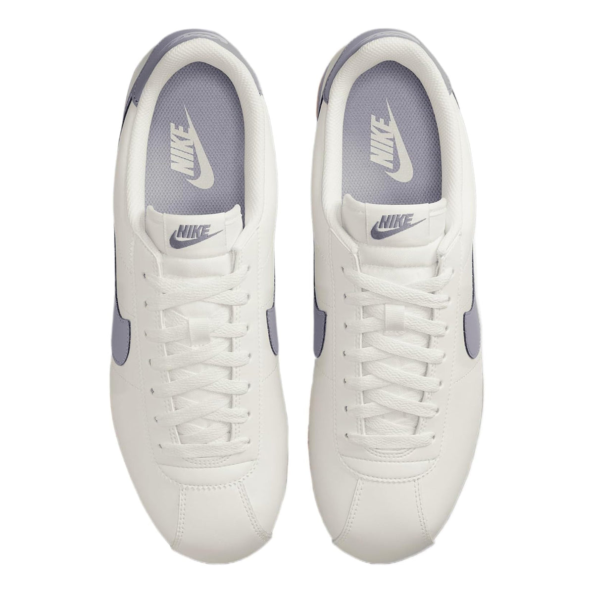 White and navy Nike sneakers, NIKE logo on tongue and heel, lace-up design.