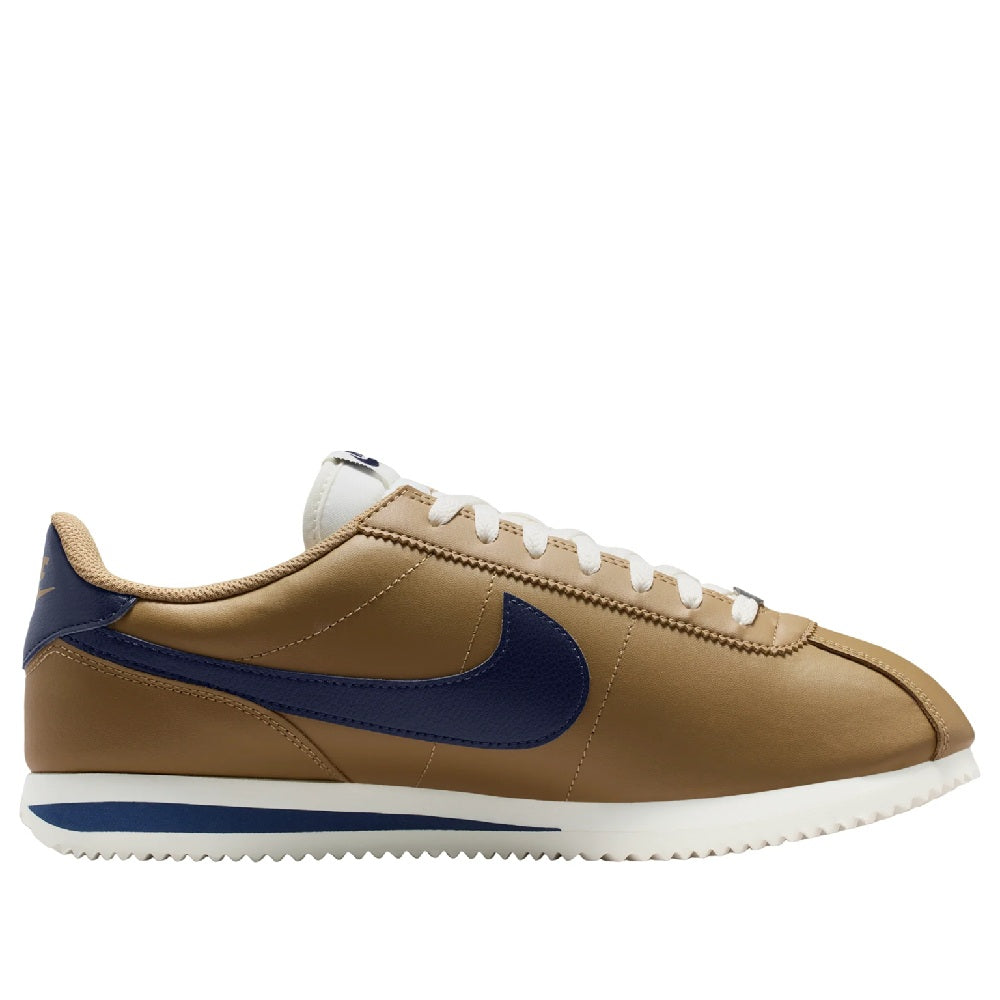Low-top sneakers with tan leather, navy swoosh, white laces, and textured white sole