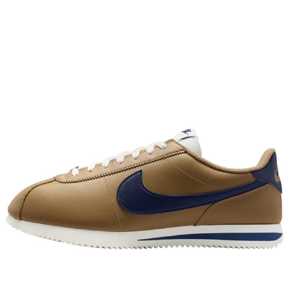 Low-top sneakers with tan upper, navy swoosh, white laces, and angled heel side profile