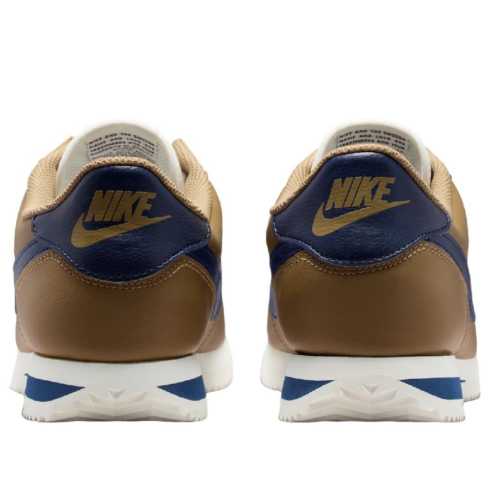 Low-top sneakers back view with tan heel, navy NIKE logo, and white midsole with blue accents