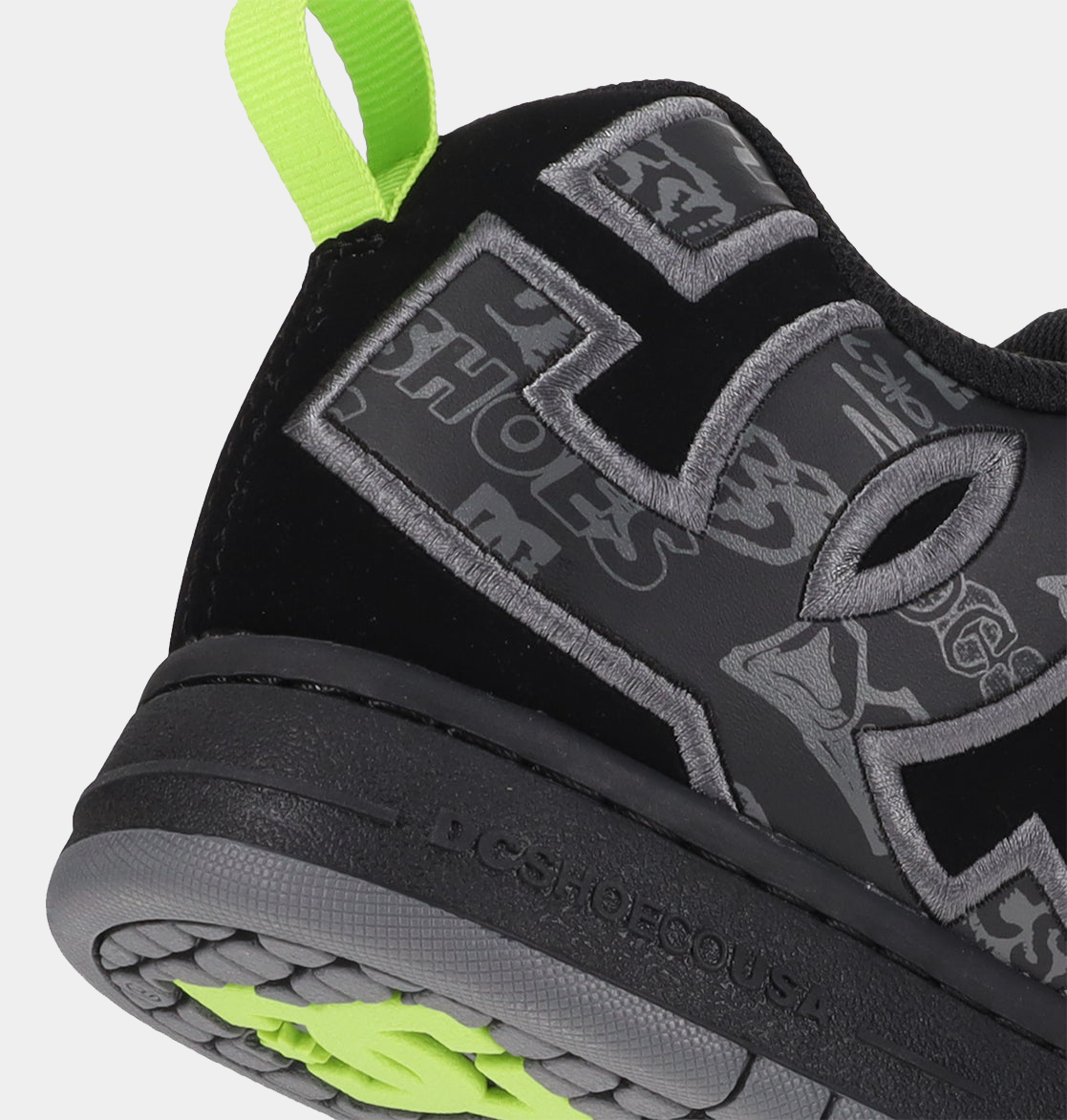 Black low-top sneaker outsole with neon green tread and gray logo detailing