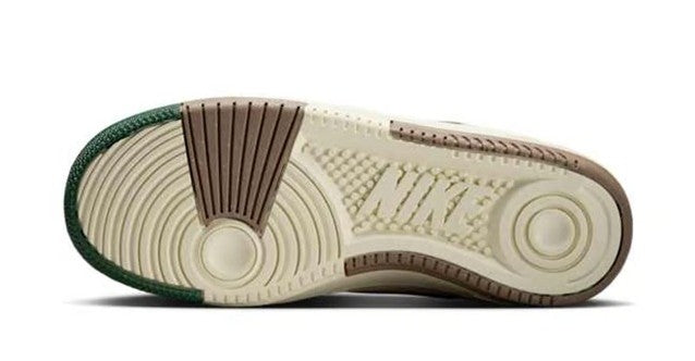 Nike sneaker outsole view with cream tread, green heel accent, and brown sidewall