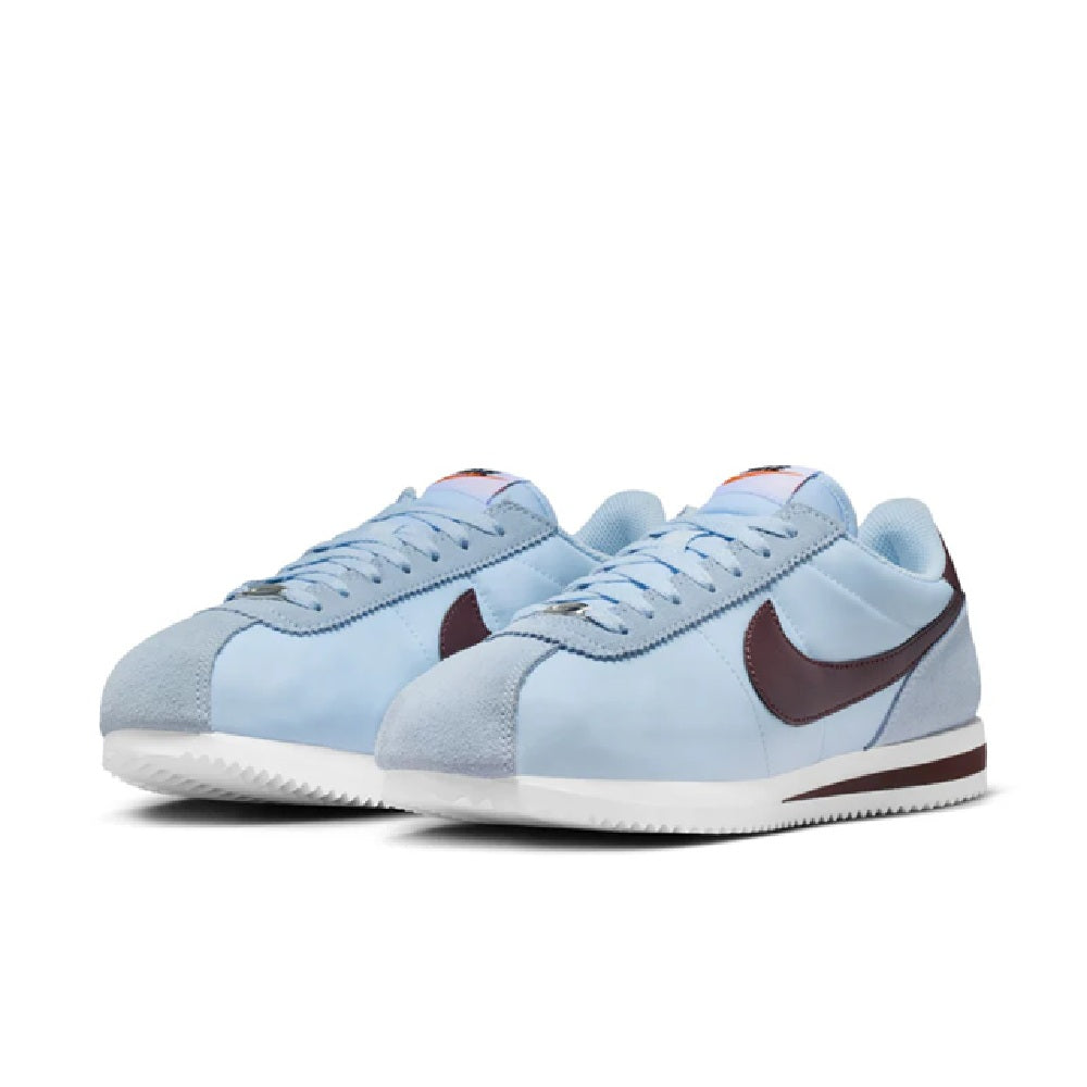 Pair of Nike Cortez sneakers in light blue with burgundy Swoosh accents and lace-up tops