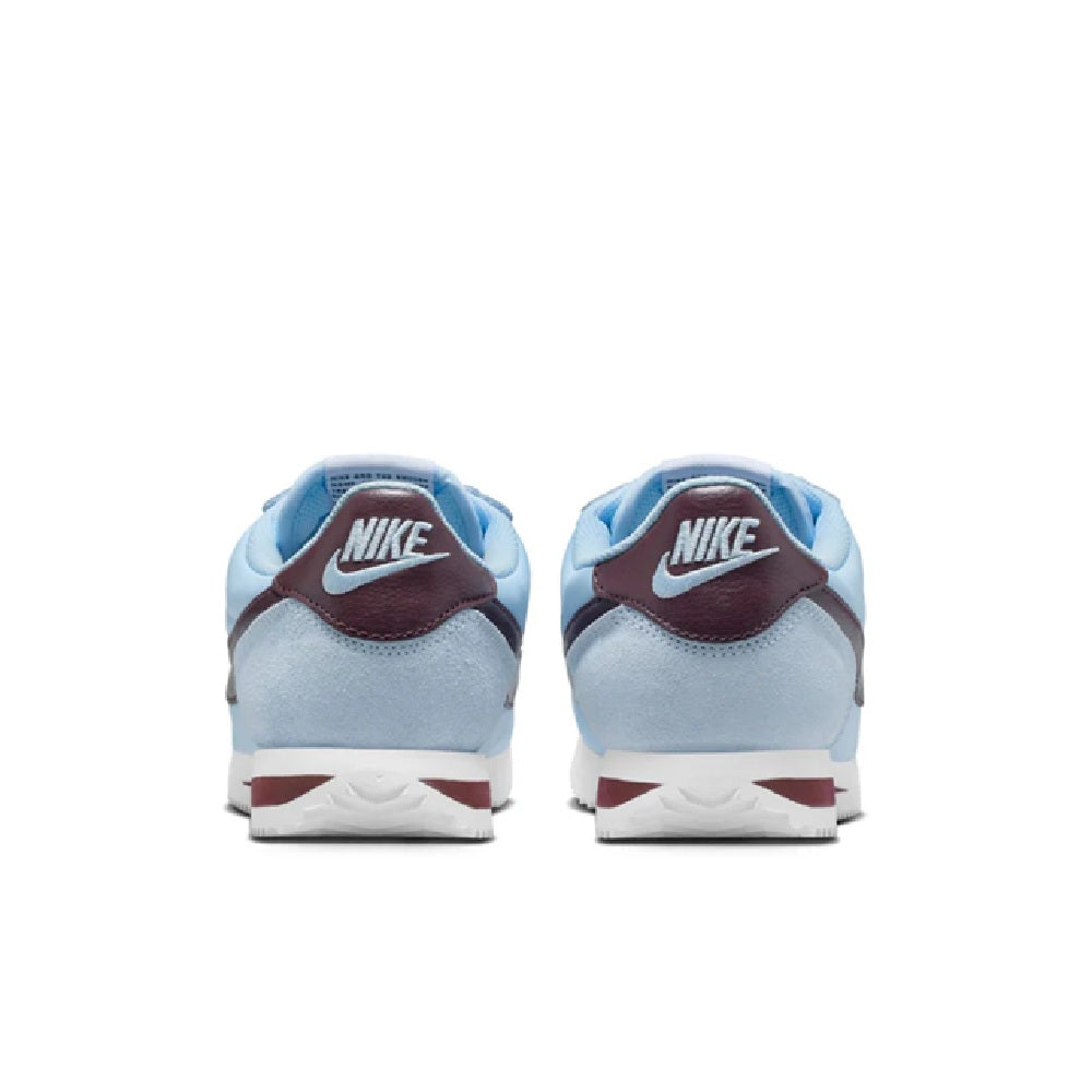Nike Cortez sneakers with light blue uppers, burgundy heel tab, and white midsole