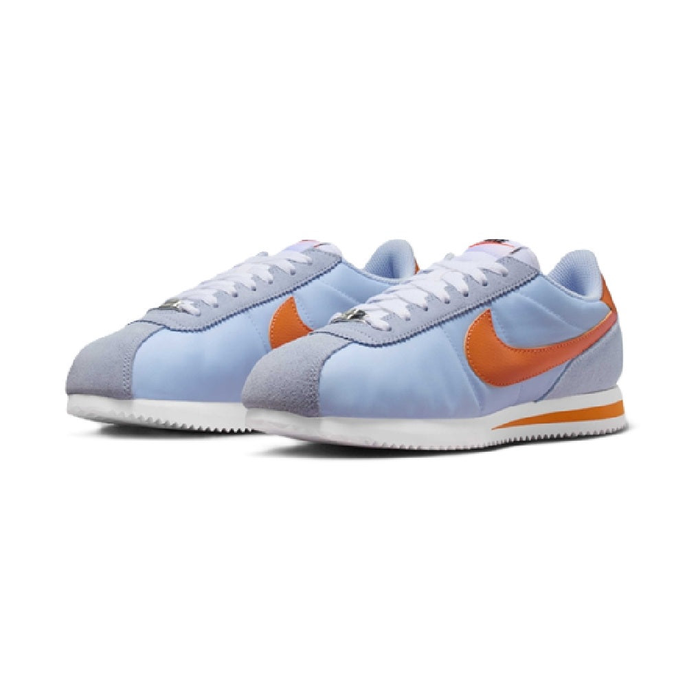 Nike Cortez sneakers pair, light blue upper with orange Swoosh and lace-up front
