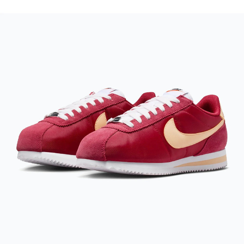 Pair of red Cortez sneakers with cream swoosh, white stitching and laces