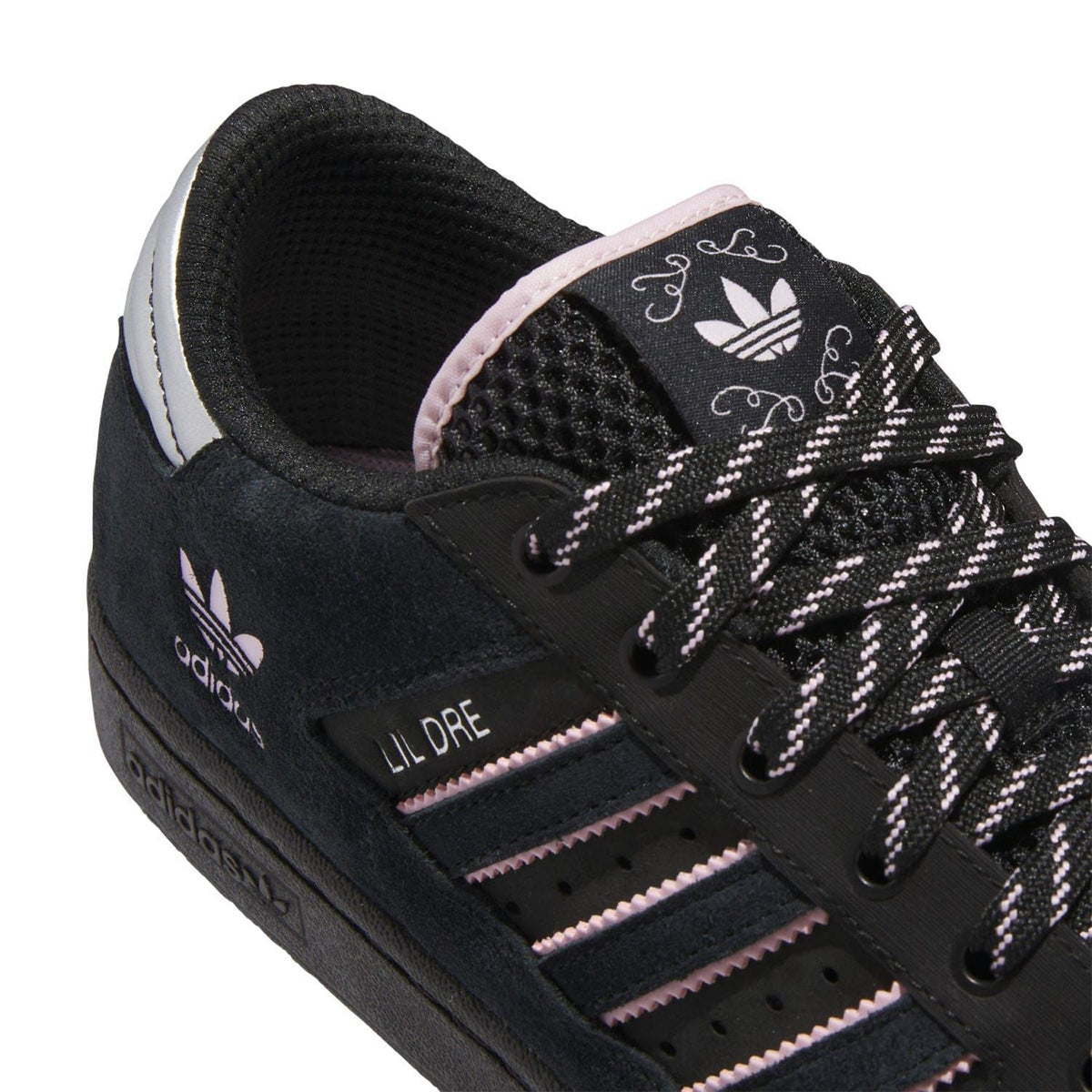 Close-up of black lace-up sneaker showing pink-striped adidas side detail