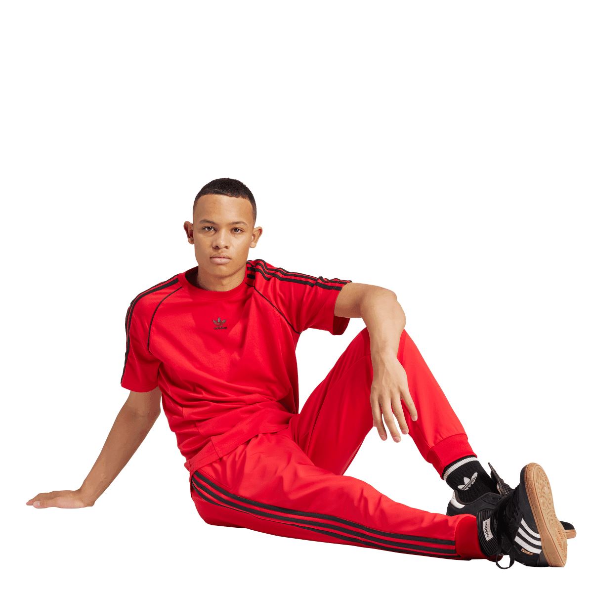 Red adidas SST T-shirt with crew neck and black sleeve stripes; model seated