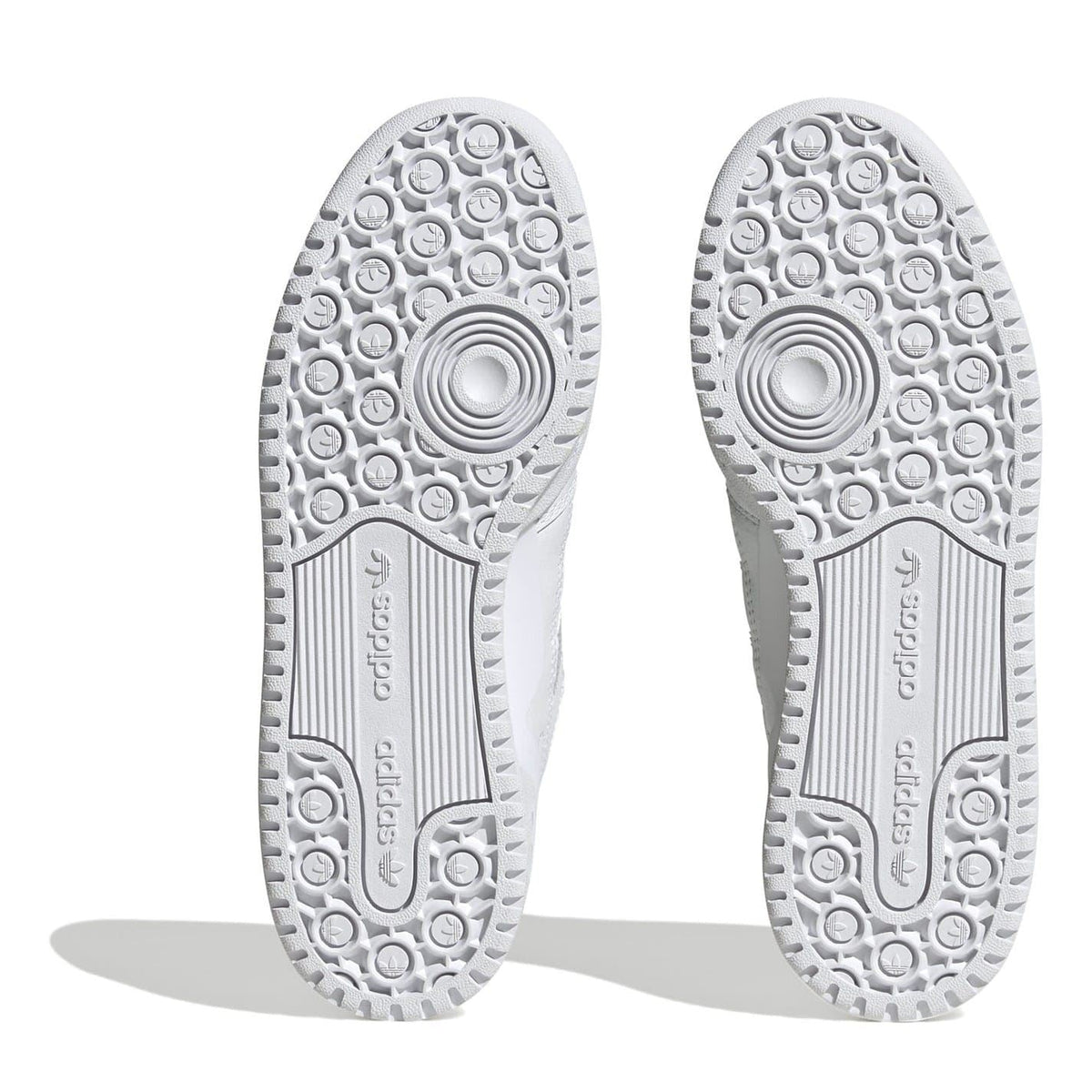White sneaker outsoles with textured tread pattern and adidas logo