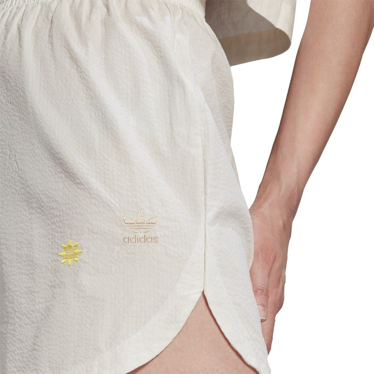 Cream shorts close-up with adidas logo and yellow star detail