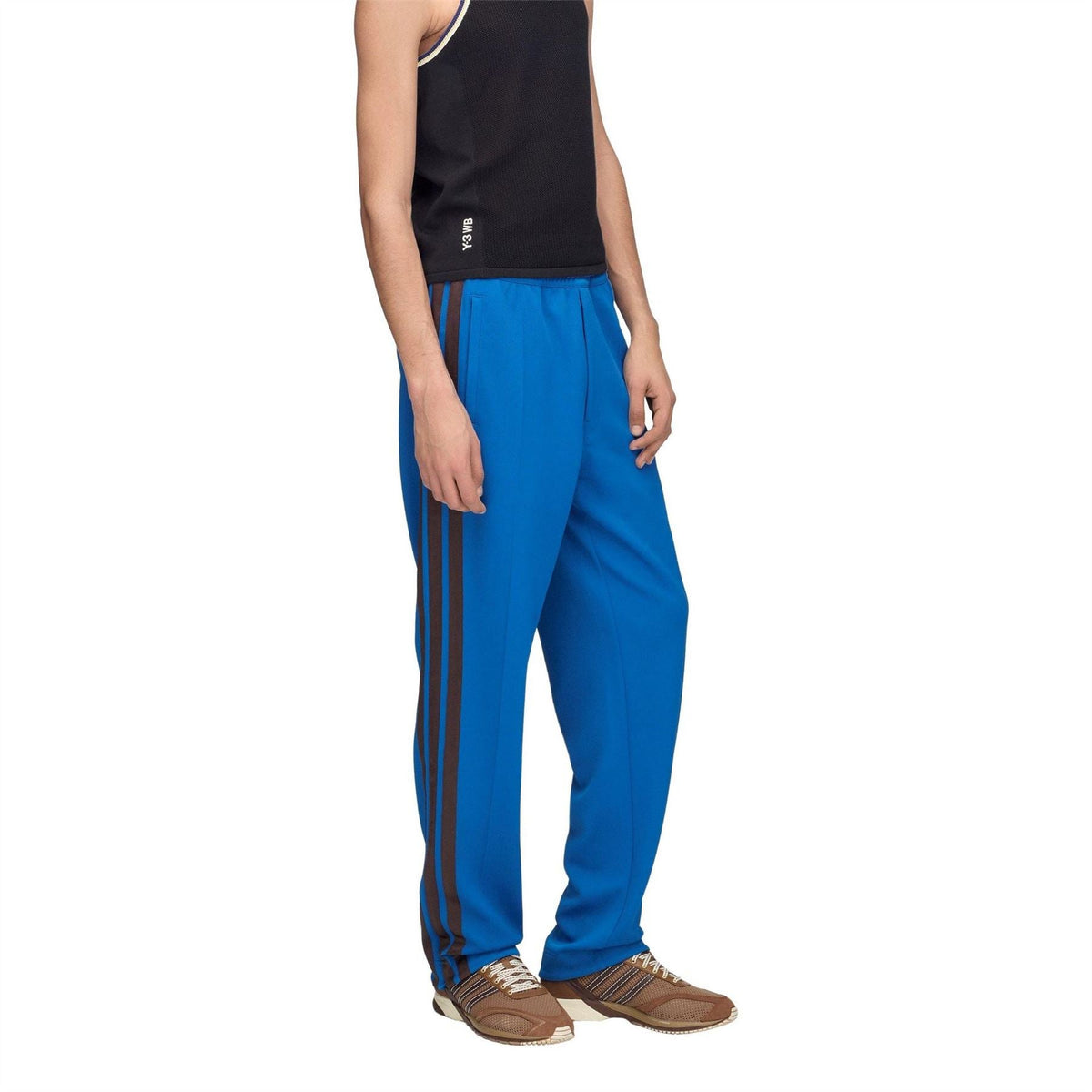 Men's blue track pants with dark side stripes, worn with sneakers