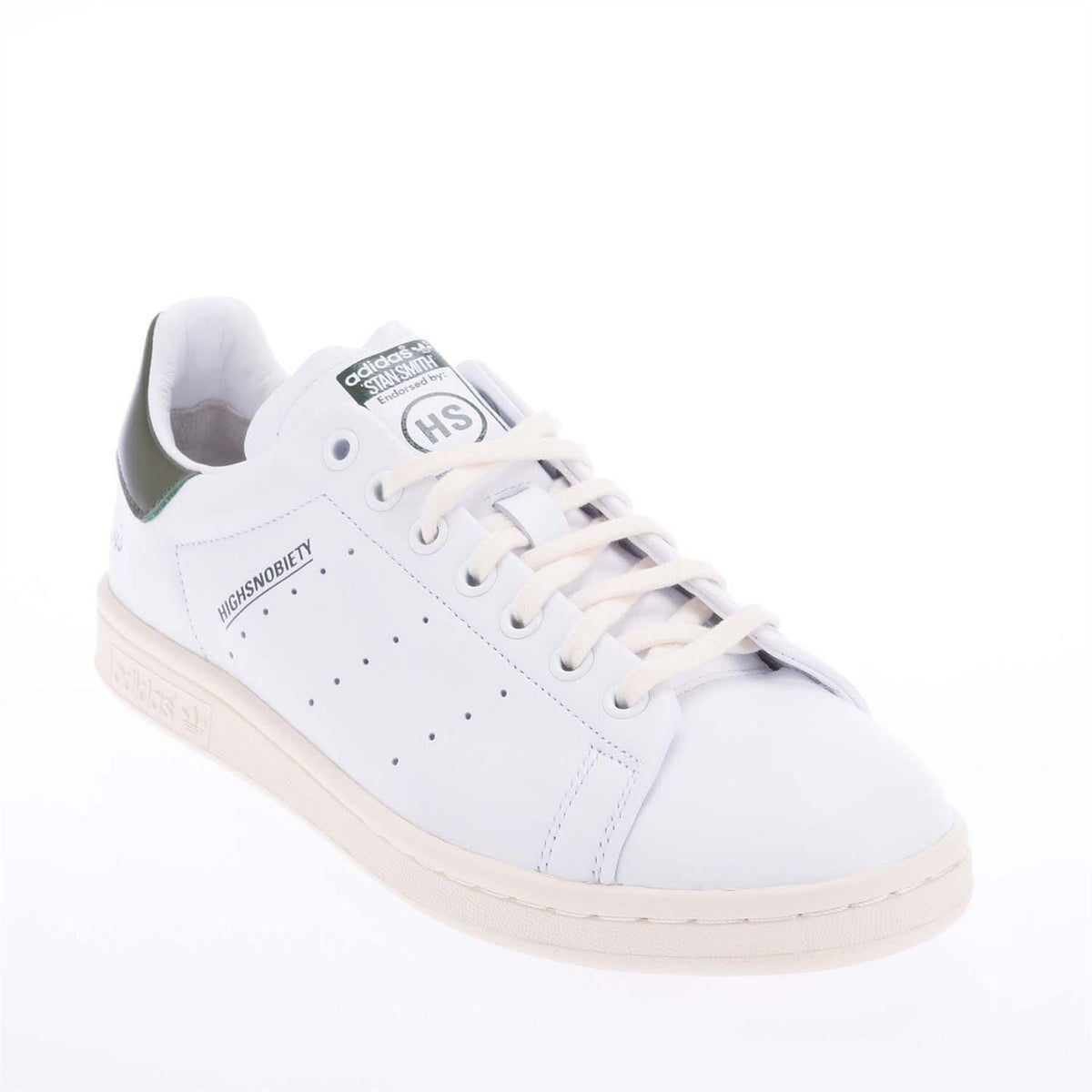 White lace-up sneaker with green-lined collar, perforated side panel, and beige sole.