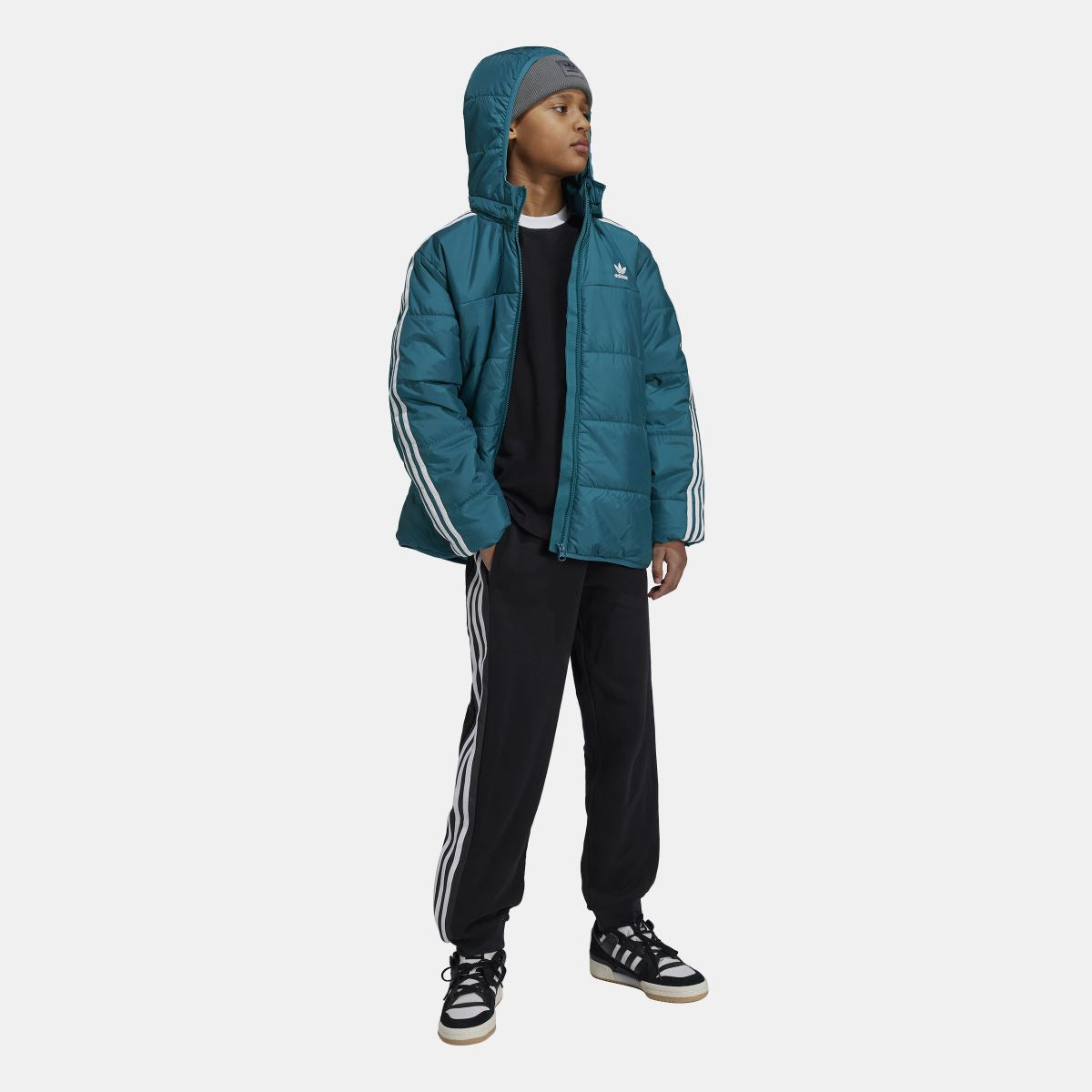 Kids teal adidas padded hooded jacket worn with black pants; full zip and stripe sleeves