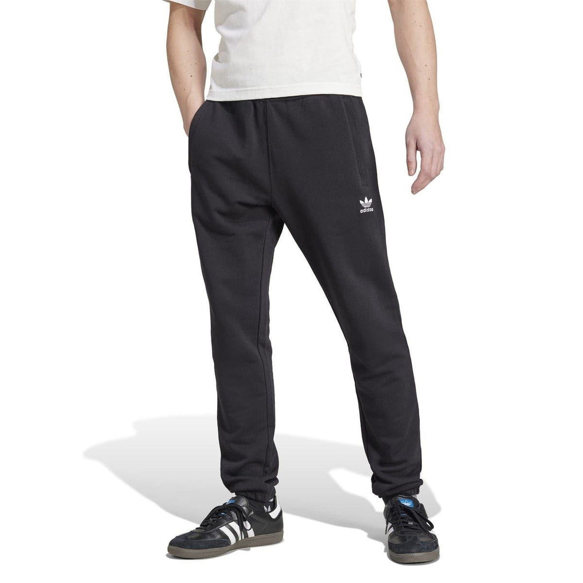 Black adidas joggers with side logo and ribbed cuffs; model wearing with sneakers