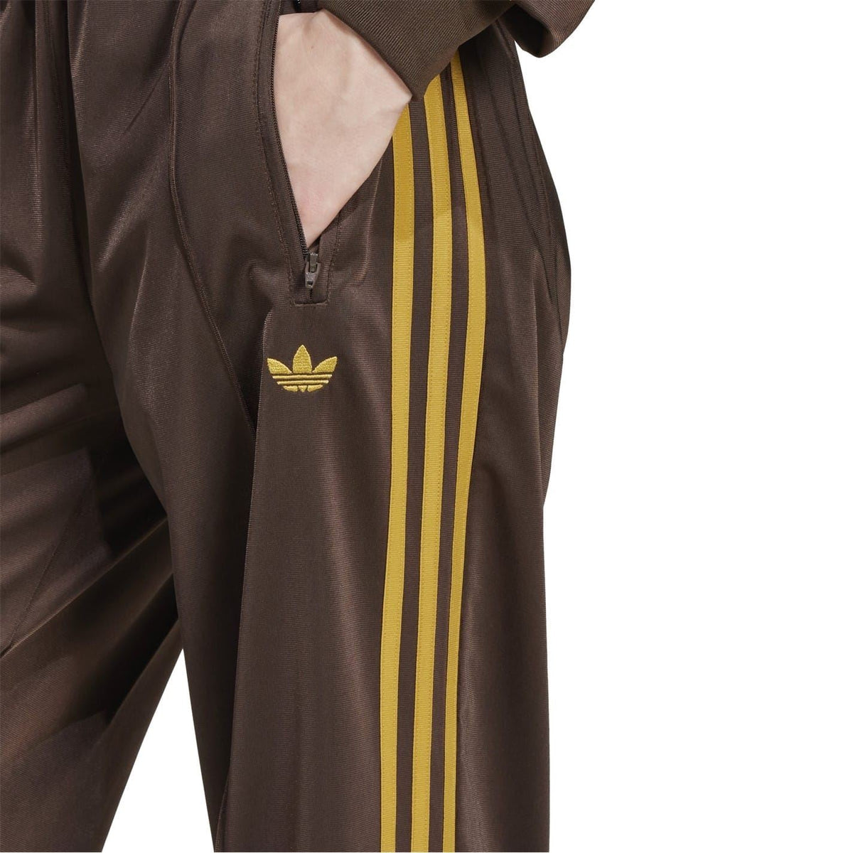 Brown track pants with gold side stripes and embroidered trefoil on chest pocket