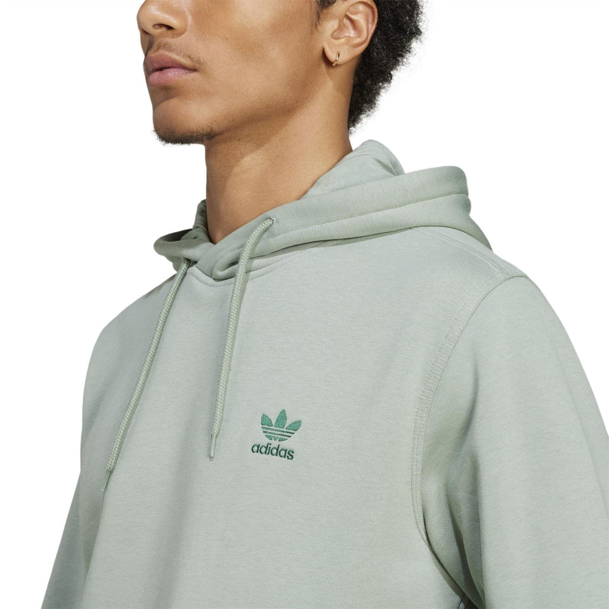 Light sage green adidas Originals Ess hooded sweatshirt close-up, adidas logo on chest