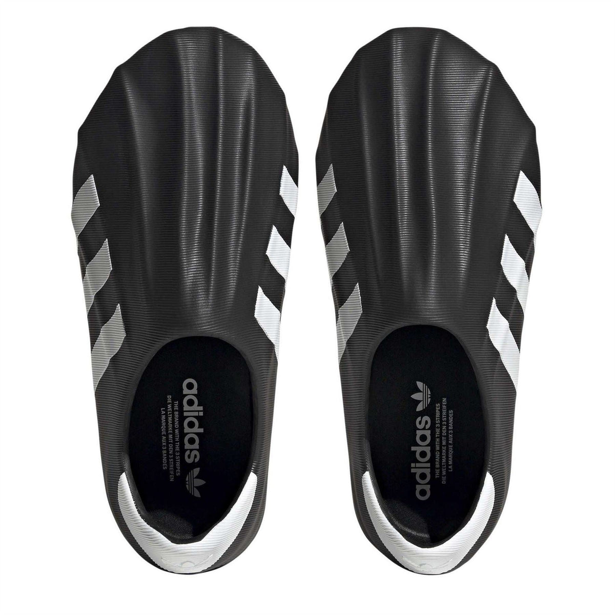 Black slip-on sneakers showing heel openings and white-striped upper panels