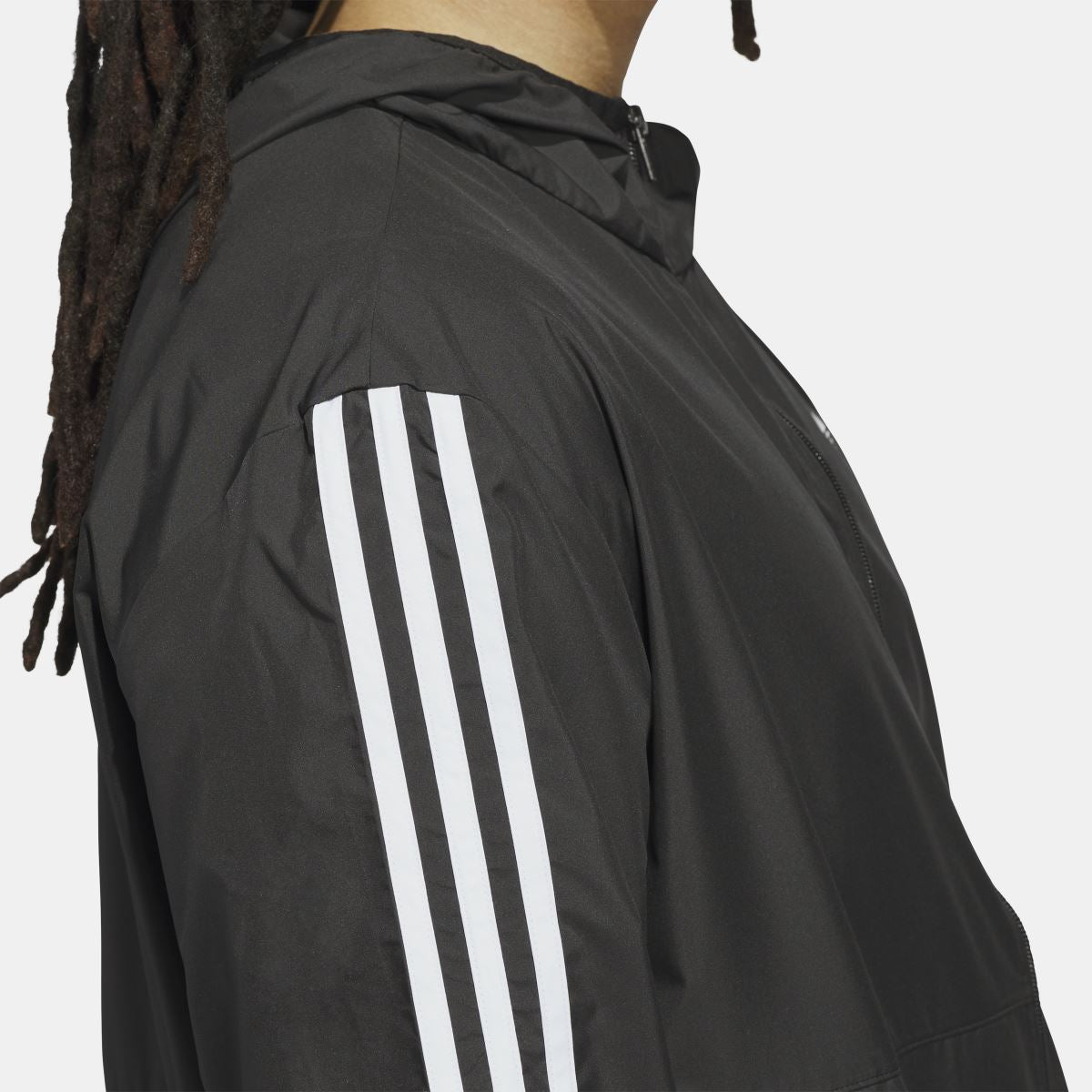 Black windbreaker jacket with white three vertical stripe panel on sleeve