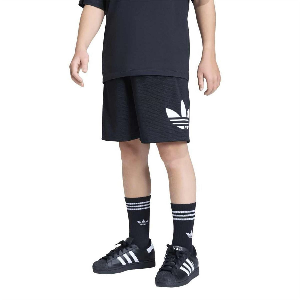 Loose black kids' shorts with side adidas logo, worn with crew socks and trainers