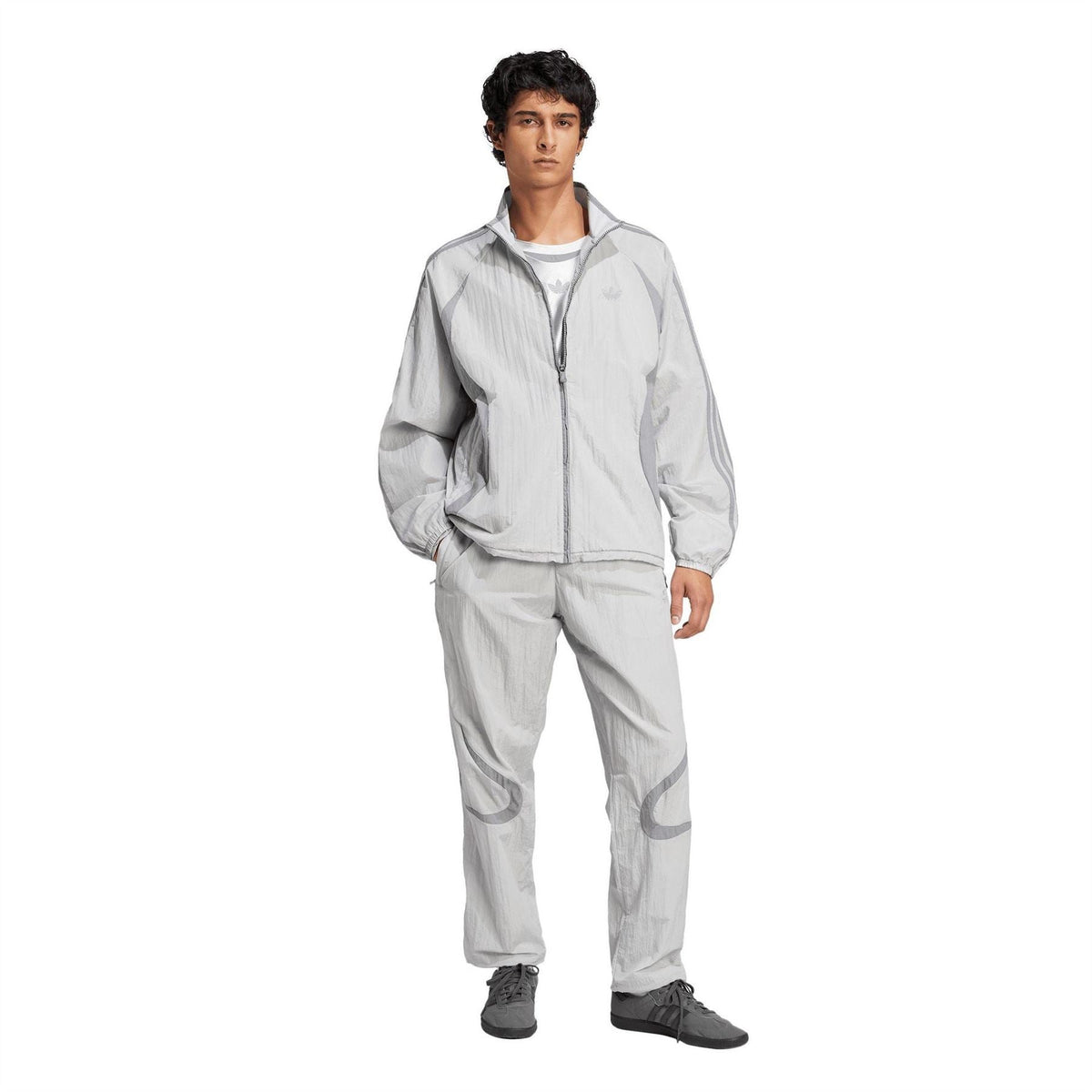 Light grey adidas Originals track pants on model, elastic waistband and logo graphic